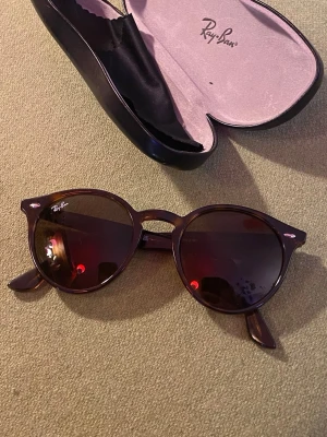 Ray-Ban solglasögon - ett par runda Ray-Ban RB2180 710/73 solglasögon i brun Havana-sköldpaddsfärg med mörkbruna glas samt ett svart fodral och putsduk.