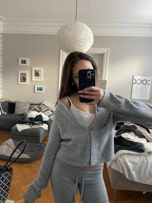 Grå croppad kofta med knappar - Mysig grå kofta i croppad modell med knäppning framtill. Tröjan är stickad och har långa ärmar med en loose passform. Perfekt för lager-på-lager och chill dagar.