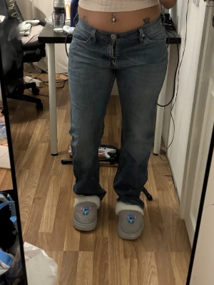 Levi's 501 blå jeans straight fit - Klassiska Levi's 501 jeans i mellanblå tvätt med raka ben och normal passform. Jeansen har fem fickor, knappgylf och tydliga kontrastsömmar. Perfekta för en avslappnad och tidlös look.