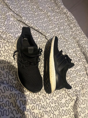 Adidas Ultraboost svarta sneakers 44⅔( Äkta) - Svarta Adidas Ultraboost sneakers med stickad ovandel och klassiska tre ränder på sidan. Skorna har vit Boost-sula för extra komfort och svart yttersula. Perfekta för dig som gillar sportig stil och vill ha riktigt sköna skor till vardagen. Inga kopior!