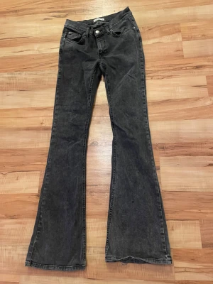 Svarta bootcut jeans från Perfect Jeans - Snygga svarta jeans från Perfect Jeans i storlek 36. Modellen har klassisk femficksdesign, hög midja och bootcut-ben som ger en schysst siluett. Jeansen är tillverkade i ett mjukt denimtyg med en mörk tvätt och silverfärgad knapp framtill.