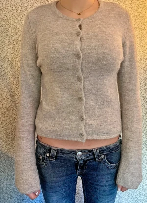 Ljusgrå stickad kofta med knappar - Supermysig ljusgrå stickad kofta med rund hals och knappar hela vägen fram. Strl. 158/164 eller XS.