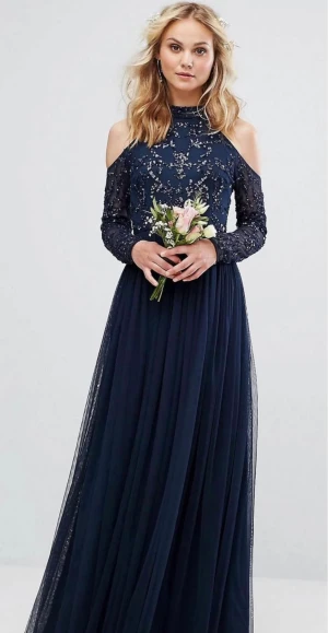 Marinblå långklänning med paljetter - Säljer en marinblå långklänning med glittriga paljetter upptill och tyll i kjolen. Klänningen har hög hals, långärmade mesh-ärmar och snygga cut-outs vid axlarna. Perfekt för bal eller student! Snygg passform och elegant look.