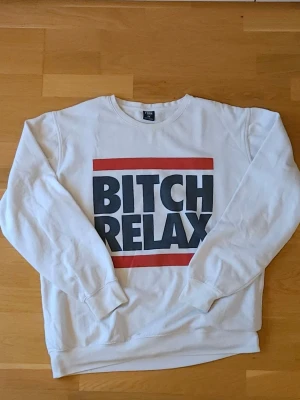 Vit sweatshirt - Säljer en vit sweatshirt från med stort tryck på bröstet. Tröjan har rund halsringning och långa ärmar. Perfekt statement-plagg för dig som vill sticka ut. Köpt på herravdelningen, Taket passform och känns mer som en L än en XXL