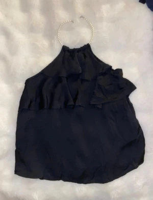 Svart linnetopp med pärlband från Zara, XS - Säljer en svart linnetopp med volangdetaljer. Toppen har ett pärlband runt halsen som ger en extra touch. 