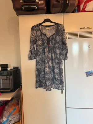 Mörkblå kortklänning med paisleymönster - Supersöt mörkblå kortklänning från Odd Molly med vitt paisleymönster, trekvartsärm och v-ringning. Klänningen har knappar framtill, liten rosett och dragkedja i sidan. Tunt och luftigt material, perfekt för varma dagar. Från märket Odd Molly. Storlek 2 som enligt deras storleksguide motsvarar en M. Mycket fint skick, jag hittar inga synliga anmärkningar eller defekter. 