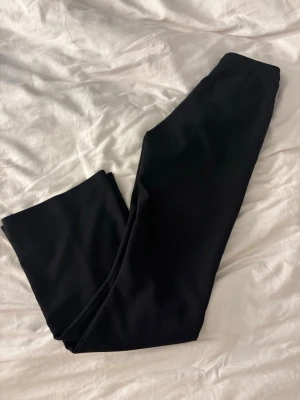 Svarta kostymbyxor Gina Tricot XS - Snygga svarta kostymbyxor från Gina Tricot i storlek XS. Klassisk rak passform med pressveck och dragkedja fram. Perfekt för dig som gillar stilrena och enkla byxor med en clean look. Materialet känns mjukt och har en lätt stretch.