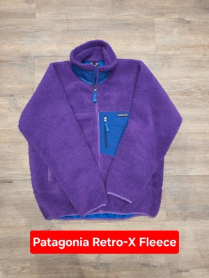Patagonia Retro Pile Fleece Jacket Purple Boxy Fit Outdoor Vintage - Iconic Patagonia fleece with that unmistakable retro outdoor vibe – bold color, boxy cut, and cozy pile texture that never goes out of style. Patagonia Retro Pile full-zip fleece jacket in deep purple with contrasting blue chest pocket and zips. Perfect for layering, streetwear fits, or everyday outdoor use. ⭐️ ORIGINAL ⭐️  📏 Measurements: Length (A): 72 cm Width / Chest (D): 63 cm Shoulder to cuff (B): 61 cm Pit to cuff (C): 56 cm  ✅ Condition: New without tags ✅ 📐 Size: L