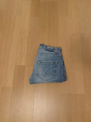 Blå jeans från Dondup Limited Edition - Säljer ett par snygga blå jeans från Dondup Limited Edition. De har klassisk femficksdesign, raka ben och ljus tvätt med subtila slitningar. Jeansen har slim passform och är tillverkade i mjukt jeanstyg med Dondup-logga på insidan. Skick 8,5/10 sparsamt använda. Pris kan diskuteras hör av dig vid frågor