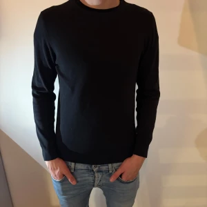 Svart stickad tröja från Bläck - En stilren svart stickad tröja från Bläck i storlek S. Tröjan har rund halsringning och långa ärmar, perfekt för lager-på-lager eller som den är. Enkel och klassisk design som funkar till det mesta.