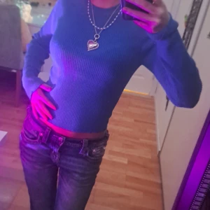 Na-kd topp blå - Säljer en blå croppad långärmad topp med ribbad struktur. Toppen har en tight passform och rund halsringning, perfekt att styla med jeans eller kjol. Enkel och stilren design som ger en fräsch look. Inga skador, använd två gånger.