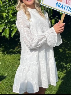 Studentklänning - Nyskick - Säljer denna populära klänningen som säljer slut fort. supersöt vit kortklänning med blommigt broderi och volangdetaljer. Jag har använt denna en gång och den är i ett nyskick!