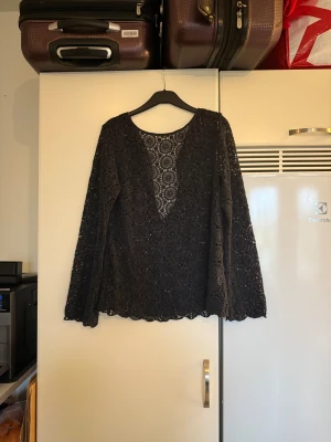 Svart spetsblus med cirkelmönster - Säljer en svart blus med lång ärm i genombruten spets och cirkelmönster. Blusen har rund halsringning och är tillverkad i ett tunt, spetsigt material som ger en cool transparent look. Perfekt för dig som gillar detaljer och vill sticka ut med snyggt mönster. Från märket Odd Molly. Storlek 2 som enligt deras storleksguide motsvarar en M. Mycket fint skick, jag hittar inga synliga anmärkningar eller defekter. 