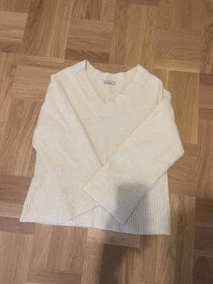 Vit stickad v-ringad tröja  - Mysig vit stickad tröja från Gina Tricot tre premium quality med breda ribbade muddar och v-ringad hals. Tröjan har lång ärm och en loose passform som ger en chill vibe. 