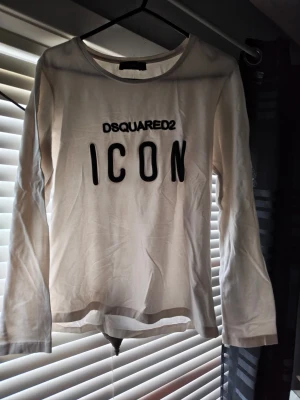 Vit långärmad topp D2 ICON - Vit långärmad topp från D2 med svart text 'ICON' framtill. Klassisk rund halsringning och rak passform. Tillverkad i mjuk bomull som känns skön mot huden. Perfekt för dig som gillar statement-plagg och vill sticka ut.