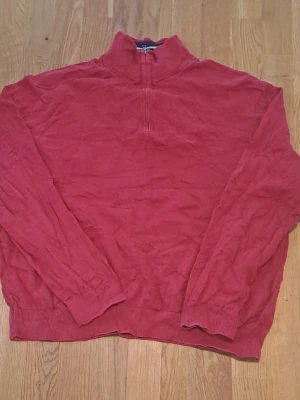 Röd halvzip tröja med hög krage - Säljer en röd långärmad halvzip från Natica i 100% bomull. Tröjan har ribbade muddar vid ärmslut och nederkant, samt en avslappnad passform. Storlek Xl men känns som M