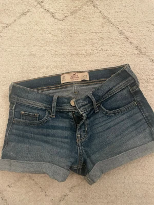 Mörkblå jeansshorts från Hollister - Snygga mörkblå lågmidjade, korta jeansshorts från Hollister. Jätte bra skick, säljer pga råkade köpa fel storlek. Uppvikta benslut men går även att vika ner/upp mer om man vill.  Rakt över: 36cm  Fram tills benet: 19cm