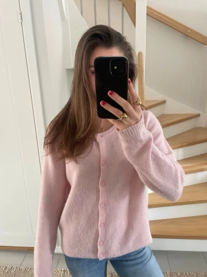 Ljusrosa stickad kofta  - Söt stickad ljusrosa kofta med rund halsringning och knappar.  Från Lager 157. 
