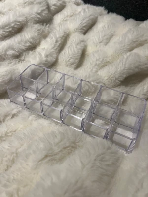 Transparent sminkorganiserare i plast - Praktisk transparent sminkorganiserare med 12 fack, perfekt för att hålla ordning på borstar, läppstift eller andra små skönhetsprylar. Tillverkad i klar plast med rektangulär form som passar snyggt på sminkbordet eller i badrummet.