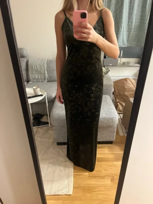 Velvet Maxi Dress - En jättefin och skön klänning från Gina Tricot. Modellen är Velvet Maxi Dress i DK green. Den är i ett fint grönt velvet material med mönster av blommor. Banden kan justeras. Stretchight material vilket gör att den ger en fin figur.  Helt ny med prislapp kvar. Jag är 168 cm för referens Strlk M
