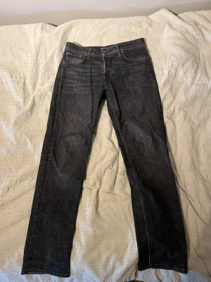 Gråsvarta raka jeans från Jack & Jones - Snygga mörkblå jeans från Jack & Jones med klassisk rak passform och fem fickor. Jeansen har kontrastsömmar och är tillverkade i slitstark denim. Perfekta för dig som gillar en tidlös och enkel stil. Storlek: 30/30