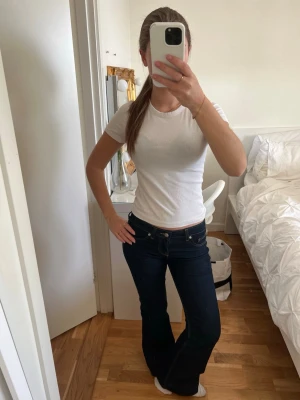 Vit ribbad t-shirt i bomull - Snygg vit ribbad t-shirt med rund hals och korta ärmar. T-shirten är figurnära och passar perfekt till jeans eller kjol. Tillverkad i mjuk bomull som känns skön mot huden.