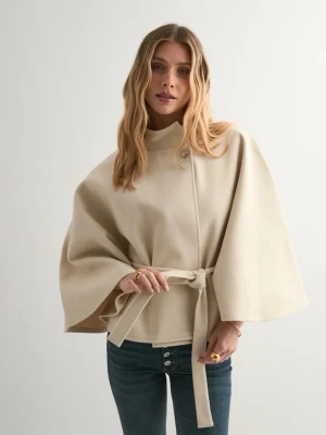 Beige cape-kappa med knytskärp - Stilren beige cape-kappa med vida ärmar och knytskärp i midjan. Hög krage och minimalistisk design, perfekt för lager-på-lager. Kappan har en knappdetalj vid halsen och är tillverkad i ett mjukt, strukturerat tyg.