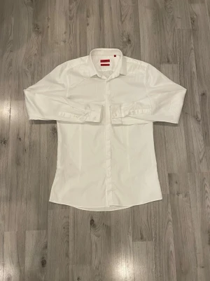 Vit klassisk skjorta med knappar - Snygg vit skjorta med klassisk krage och knäppning framtill. Skjortan har långa ärmar med manschett och är tillverkad i ett lätt och bekvämt material. Perfekt för en stilren look.