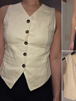 Ljusgul väst med knappar - Stilren ljusgul väst från &other stories med djup V-ringning och fem stora bruna knappar framtill. Västen har figurnära passform och spetsig nederkant. Tillverkad i ett glansigt tyg som ger en elegant känsla. Perfekt för att lyfta din outfit.