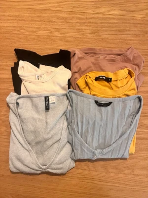 6-pack t-shirts i olika färger - Säljer ett paket med 6 toppar i olika färger och modeller. Färgerna är svart, vit, beige/rosa, gul, ljusblå och gråblå. Märkena inkluderar Divided, Bik Bok, Shein och Gina Tricot. Materialen varierar mellan bomull och ribbad trikå. 