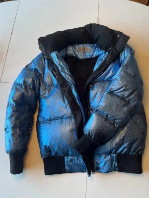 Blå metallic dunjacka Calvin Klein Jeans - Säljer en varm och skön dunjacka i unik metallic blå färg! ❄️Jätteskön hög krage. Lätt att bära och figurnära. Använd en del, färgen har skavts av på ärmarna, se sista bilden. 