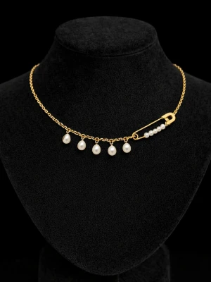 Guldfärgat halsband med pärlor - Unikt halsband med guldfärgad kedja och dekorativa vita pärlor. En cool detalj är säkerhetsnålen som också är dekorerad med små pärlor. Perfekt för dig som gillar trendiga och personliga smycken.