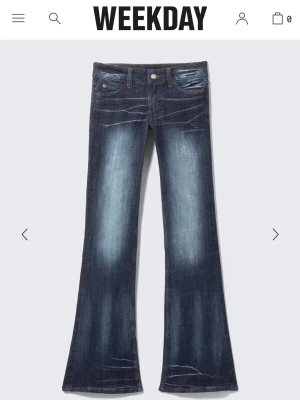 Blå bootcut jeans från Weekday - Säljer ett par slutsålda blå bootcut jeans från Weekday med snygga slitningar och utsvängda ben. Jeansen har klassisk femficksdesign och knappgylf. Perfekta för dig som gillar en retroinspirerad look.