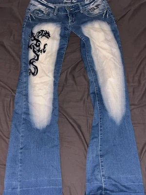 Crazy age jeans med broderi - Säljer ett par blå bootcut jeans från Crazy Age med ljusa slitningar framtill och bak. Low waist och bootcut Innerbens längd : 80cm midje mått : 39