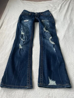 Lågmidjade jeans med slitningar  - Storlek M men passar som S på mig. Innerbensländen är 75cm, midjemåttet 39cm och grenhöjden 19cm. Inga defekter, för mer bilder/info skriv