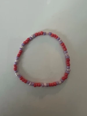 Lila och rött pärlarmband storlek S  - Ett handgjort armband med pärlor i lila och rött. 