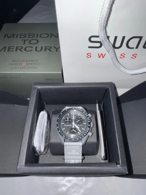 Omega x Swatch Moonswatch Mission to Mercury – Med låda - Säljer en Omega x Swatch Moonswatch Mission to Mercury. Populär modell i mörkgrå färg inspirerad av planeten Merkurius.