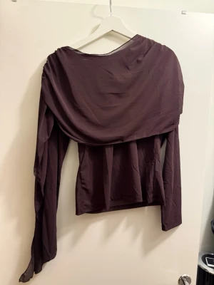 Mörkbrun draperad långärmad topp - Säljer en mörkbrun långärmad topp med snygg drapering över axlar och bröst. Aldrig använd - prislappen kvar 