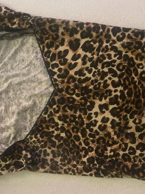 Leopardmönstrat nattlinne från Nelly - Snyggt nattlinne från Nelly med leopardmönster i brunt, svart och beige. V-ringad hals med svarta spetsdetaljer längs kanterna. Mjukt och stretchigt material som känns bekvämt mot huden. Perfekt för en chill kväll hemma.