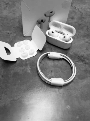 Vita Apple AirPods Pro med tillbehör - Säljer ett par vita Apple AirPods Pro med laddningsetui, extra silikontoppar i olika storlekar och en vit laddningskabel. Snygg och stilren design i plast och silikon, perfekt för trådlös musik och samtal. Helt oanvända 
