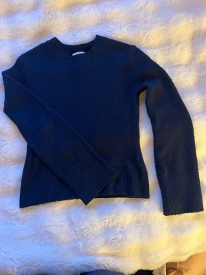 Mörkblå stickad tröja H&M XS - Mysig mörkblå stickad tröja från H&M i storlek XS. Tröjan har rund halsringning, långa ärmar och ribbstickade muddar vid ärmslut och nederkant. Tröjan har använts flitigt och är därför lite nopprig, därför säljer jag den för ett bra pris💗