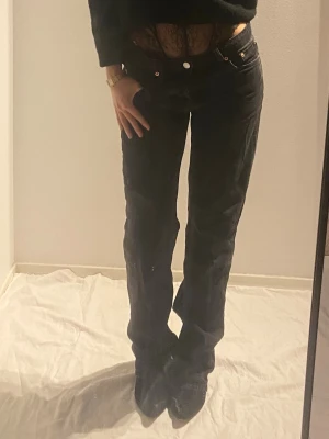 Svarta raka jeans  - Säljer ett par svarta jeans med rak passform och klassisk femficksdesign. Jeansen har normal midja och stängs med knappar. Perfekta till en avslappnad och trendig look.