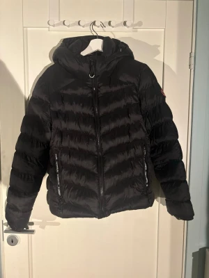 Svart dunjacka från Superdry - Superfin, varm dunjacka från superdry. Använd cirka 5 gånger VÄLDIGT liten i storleken då jag vanligtvis är en S/M och denna jackan tog jag i XL som sitter precis som en jacka ska sitta i storlek S/M! Tidigare pris= 1 100