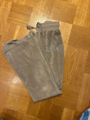 Beige mjukisbyxor med strass från Lindex - Snygga beige mjukisbyxor från Lindex med strassdetaljer i form av texten 'Love' på ena benet.