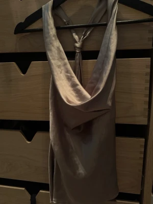 Champagnefärgad satintopp med drapering - Säljer en snygg champagnefärgad satintopp med draperad urringning och smala axelband som knyts i nacken. Från en gammal kollektion av zara, dm ifall fler bilder!💖