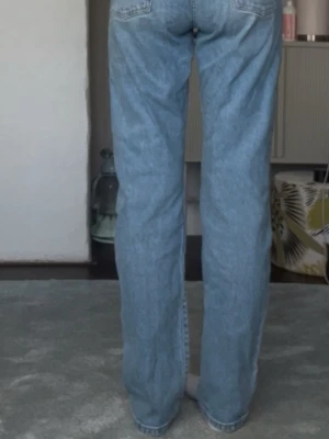 Ljusblå raka jeans från Levi's - Ljusblå jeans med rak passform och klassisk femficksdesign från Levi's. Jeansen har hög midja och stängs med knapp och dragkedja. Perfekta för en avslappnad och trendig look.