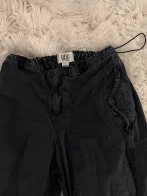 Snygga cargo byxor BDG Parachute Pants i tvättad svart - Säljer ett par sjukt snygga parachute-byxor från BDG (Urban Outfitters). De har den perfekta "washed black" färgen och en skön, lös passform. Justerbara dragskor både i midjan och vid bensluten så att man kan styla dem precis som man vill!