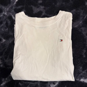 Vit Tommy Hilfiger T-shirt - Vit Tommy Hilfiger T-shirt i strl S, använd ett fåtal gånger och har lite missfärgningar runt ärmarna, men inget som syns, hör gärna av er vid frågor elr funderingar!