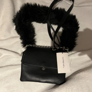 Väska Ivyrevel - svart axelväska från Ivyrevel med pälsdetalj på axelremmen, har också ett längre band som går att ta av och på. Väskan e som oanvänd har även prislapp kvar, har lite repor på metallkedjan men inget som syns. Säljs för den ej kommer till användning som jag trodde den skulle! Får plats med mobil, plånbok, nycklar, lite smink osv, det man behöver om man ska gå ut till exempel. 