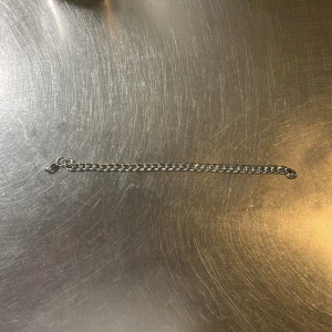Kedjearmband i silverfärg - Stilrent armband med klassisk kedjelänk i silverfärg. Armbandet har en enkel karbinhake som lås och passar perfekt för dig som gillar minimalistiska accessoarer. Länkarna är mellanstora och ger ett snyggt, tidlöst intryck.